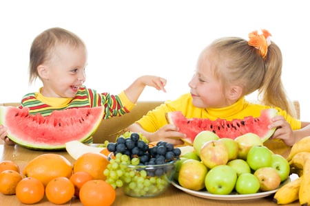 Two children eat fruit at a table on a white background,  concept of health care and healthy child nutritionの写真素材