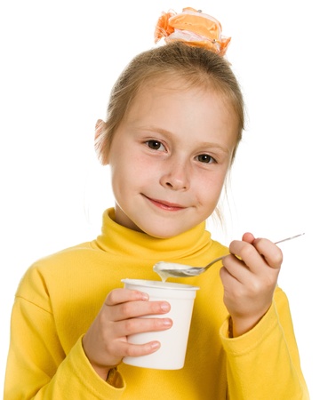 Young girl eating yogurt on a white background.の写真素材