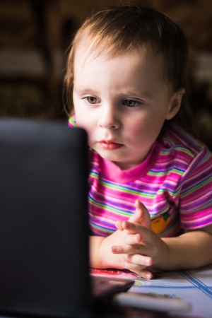 Cute baby looking thoughtfully into the laptop.の写真素材