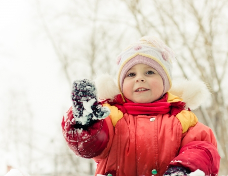 Beautiful happy kid in the red jacket in the winter outdoors.の写真素材