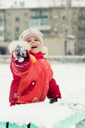 Beautiful happy kid in the red jacket hand points winter outdoors.の写真素材