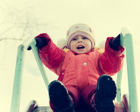 Small child is riding a roller coaster on the playground in a retro style.の写真素材