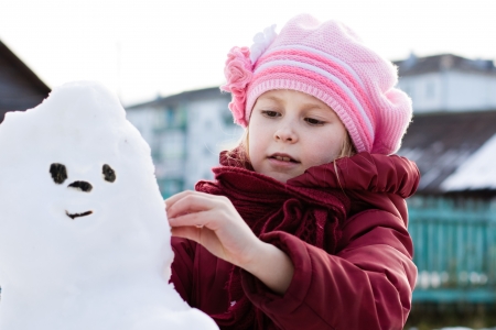Happy child with snowman in winter parkの写真素材