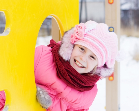 Beautiful happy kid in the red jacket in the winter outdoors.の写真素材