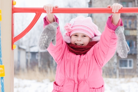 Beautiful happy kid in the red jacket in the winter outdoors.の写真素材