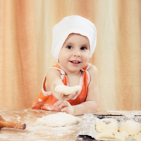 Pretty beautiful girl covered in flour makes cakes.の写真素材