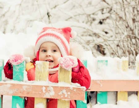 Beautiful happy kid in the red jacket in the winter outdoors.の写真素材
