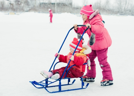 Happy kids skating and sledding in winter outdoorsの写真素材