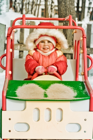Beautiful happy kid in the red warm clothing in the winter outdoors.の写真素材