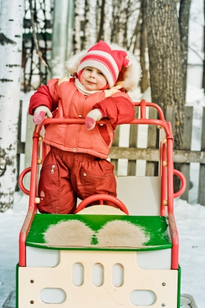 Beautiful happy kid in the red warm clothing in the winter outdoors.の写真素材