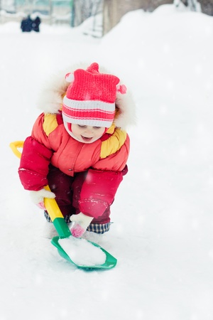 Kid digs snow shovel in the winter.の写真素材