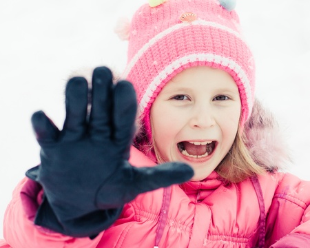 Beautiful happy kid in the red jacket in the winter outdoors.の写真素材