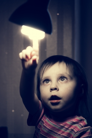 Little child points his finger at a lighted lamp.の写真素材