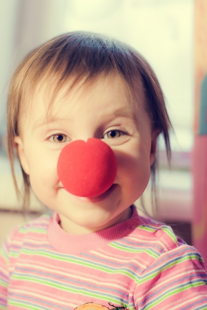 Kid with red nose clown fooling around.の写真素材