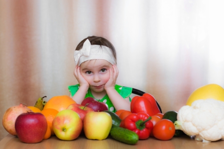 Happy Kid with vegetables and fruits sitting at the table.の写真素材