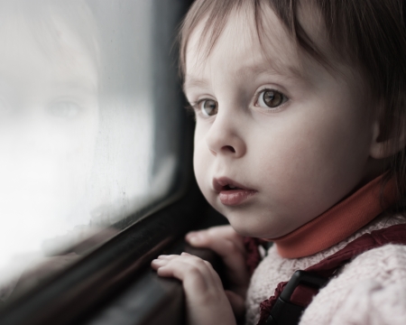 A boy rides on a train and looking out the window.の写真素材