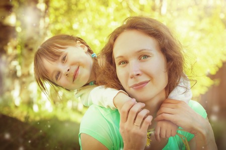 Daughter hugging mother on a bright sunny day.の写真素材
