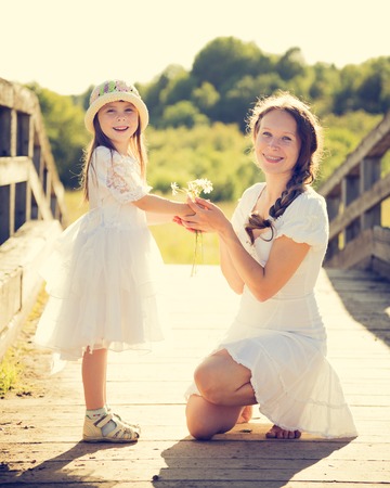 Daughter gives mother flowers on a nature.の写真素材