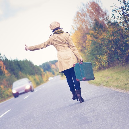 Elegant woman with a suitcase traveling the highway autumn day.の写真素材