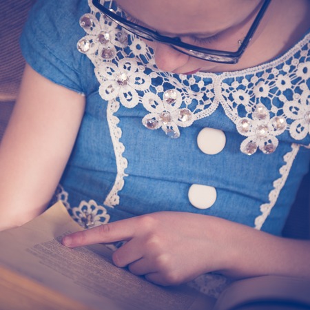 Girl reading a book at home sitting in an armchair. Photos in retro style.の写真素材