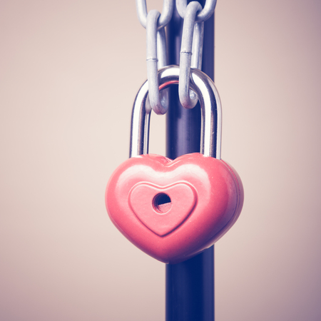 Lock in the form of a heart hanging on a chain. Photos in retro style.の写真素材