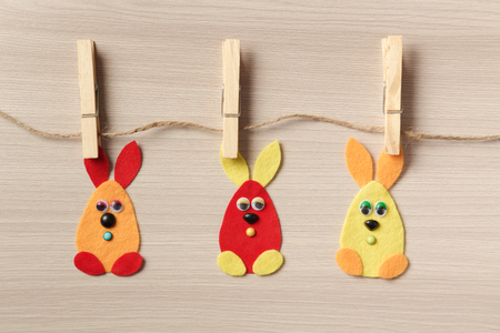 Three Easter bunny on the clips to a rope on a wooden background.の写真素材