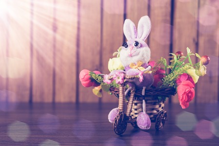 Easter bunny on a bicycle with flowers on wooden background.の写真素材