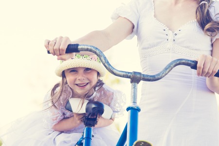 Beautiful mother and daughter traveling on a bicycle on a warm summer day.の写真素材