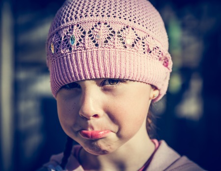 Close-up portrait of sad little girl with pursed lips. Photos in retro style.の写真素材