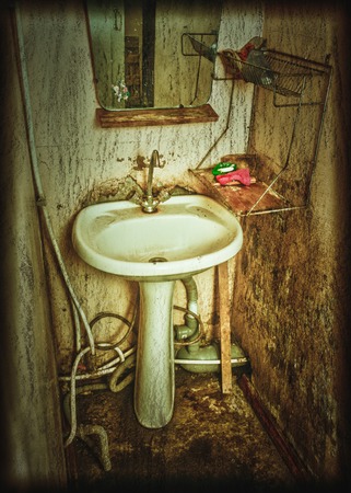 Old rusty wash basin on the dirty tile.の写真素材