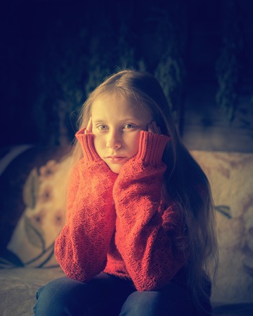 Lone teenager in warm clothing sitting on a sofa.の写真素材