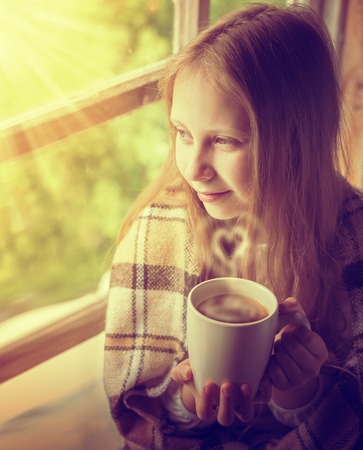 Young beautiful girl in a village house with a cup of coffee.の写真素材