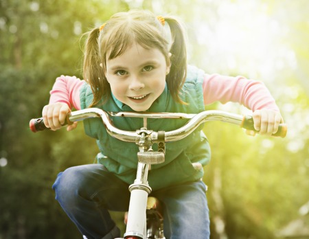 Young girl is cycling into the sunset in the park.の写真素材