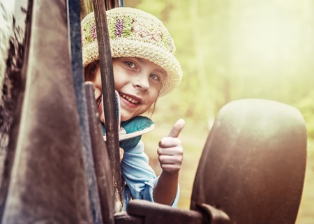 The little girl looks out the car window and shows a gesture okay.の写真素材
