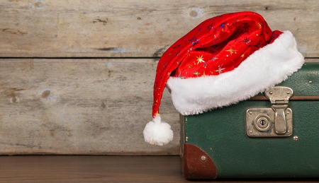Closed suitcase with a Christmas hat on a wooden background old surface.の写真素材