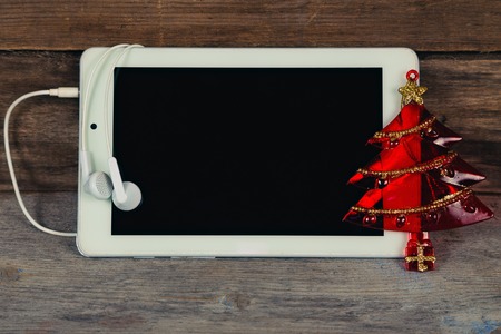 Tablet and Christmas toy on a wooden surface.