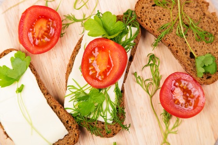 Cheese sandwich parsley dill and tomato on the table.