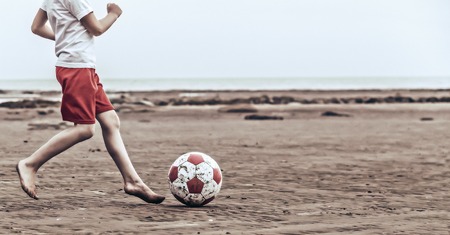 Child playing soccer on the beachの写真素材