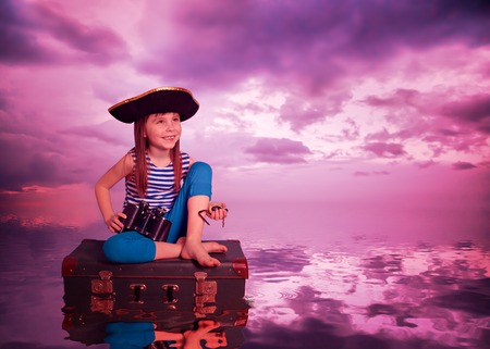 The kid travels on the sea and on the suitcase.の写真素材