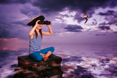 The kid travels on the sea and on the suitcase.の写真素材