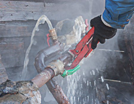 A plumber fixes a water leak on a water pipe.の写真素材