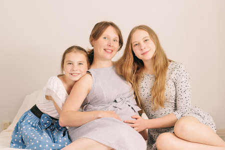 Happy kids holding belly of pregnant woman at home cozy environment.の写真素材