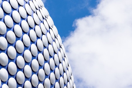 Modern sleek architecture building texture background with blue cloudy skyの写真素材