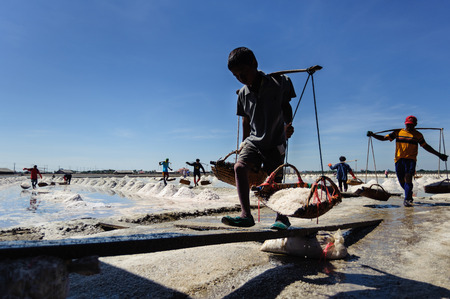 a salt farm worker bear a bucket with full of salt go to a barnのeditorial素材
