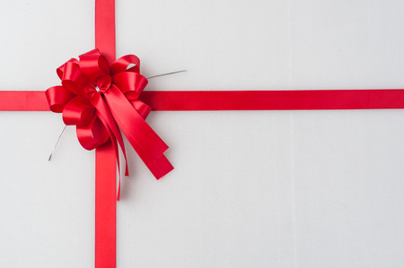 Red satin ribbon with bow on white backgroundの写真素材