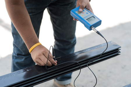 Man use coat thickness meter taking measurement on an aluminium stripeの写真素材