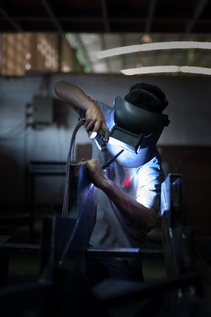 Worker wearing a protective mask welding metalの写真素材