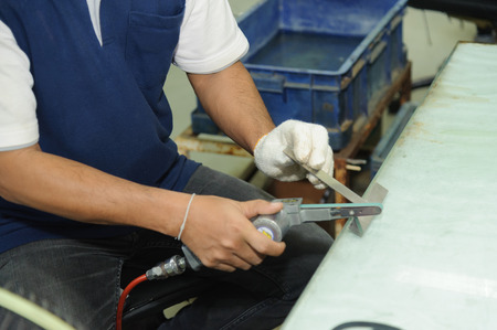 Worker using handy air belt sander. Pneumatic belt sander machine