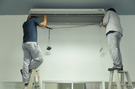 Technicians maintenance air conditioner in an officeの写真素材