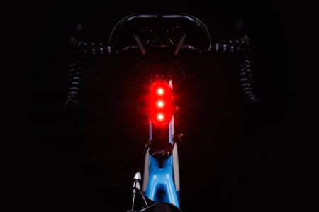 Close-up of illuminated bicycle tail light on black background